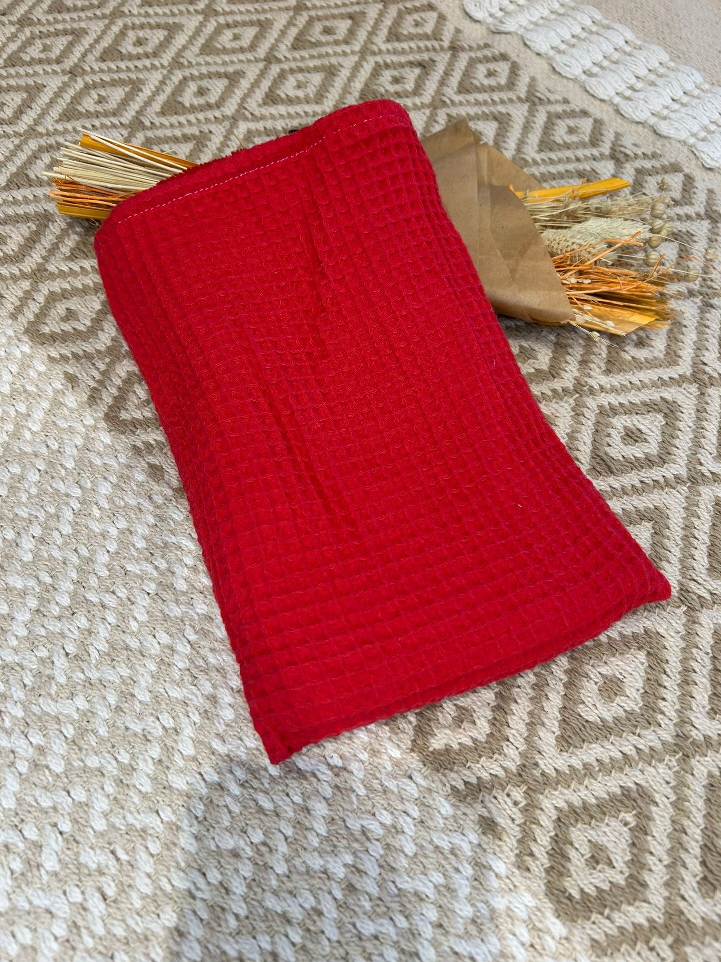 gant de toilette rouge, filet blanc et coeur sur un tapis beige et un bouquet de fleurs sécher