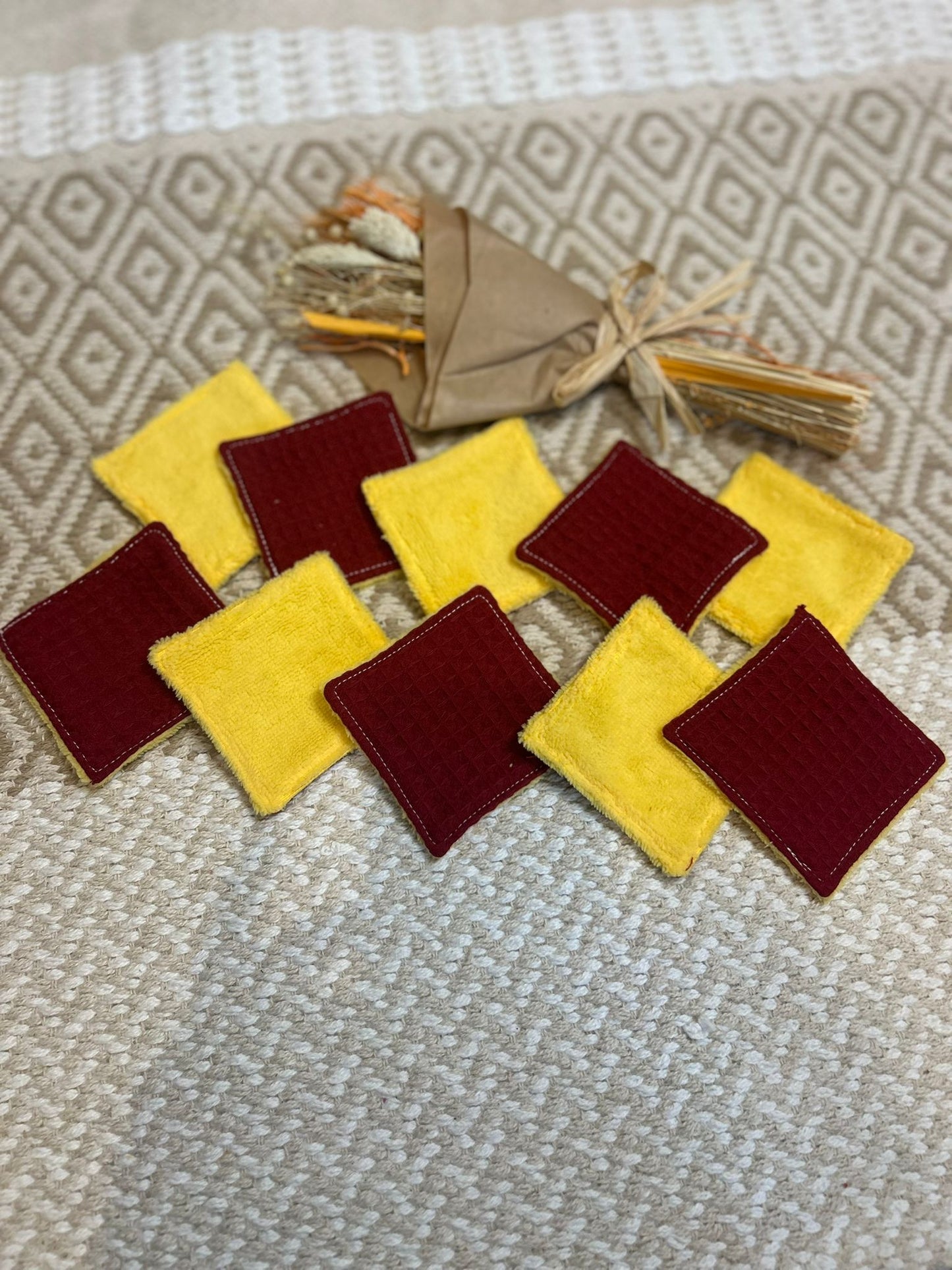 carré de coton démaquillante lavable jaune et bordeaux en coton et nid d'abeille, sur une tapis 