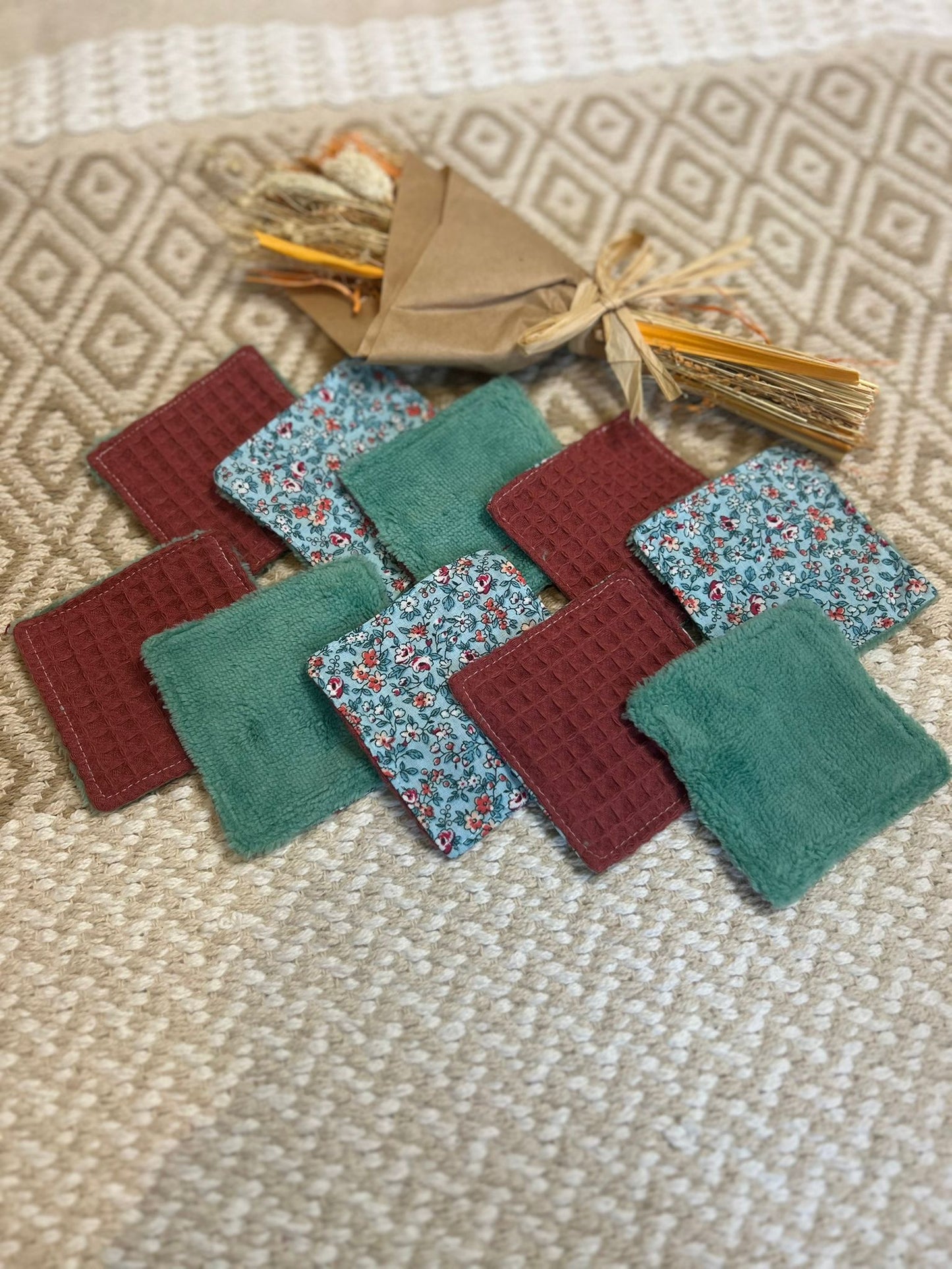 carré de coton démaquillante lavable vert et bordeaux en coton et nid d'abeille, sur une tapis 


