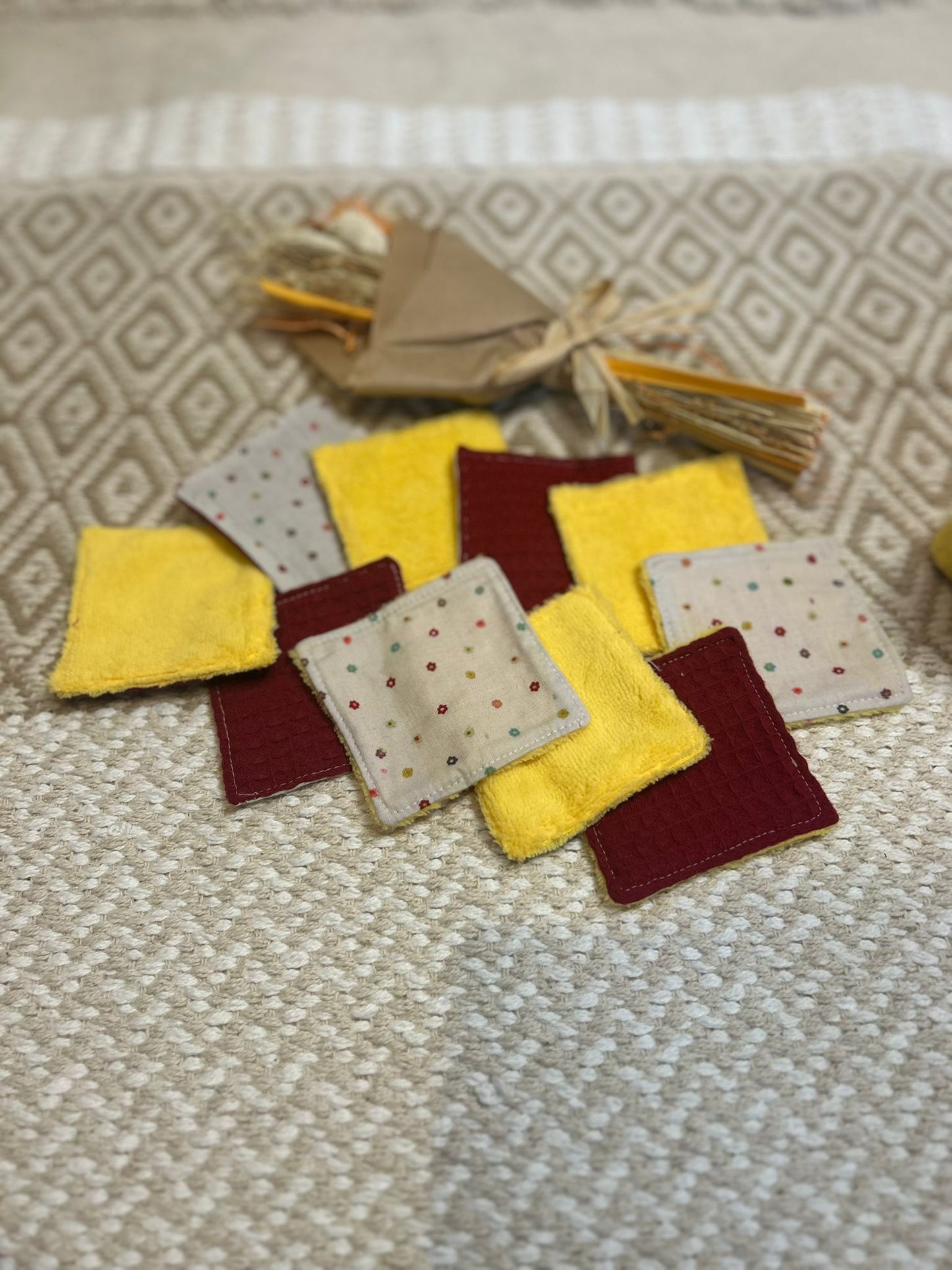carré de coton démaquillante lavable jaune et bordeaux en coton et nid d'abeille, sur une tapis 
