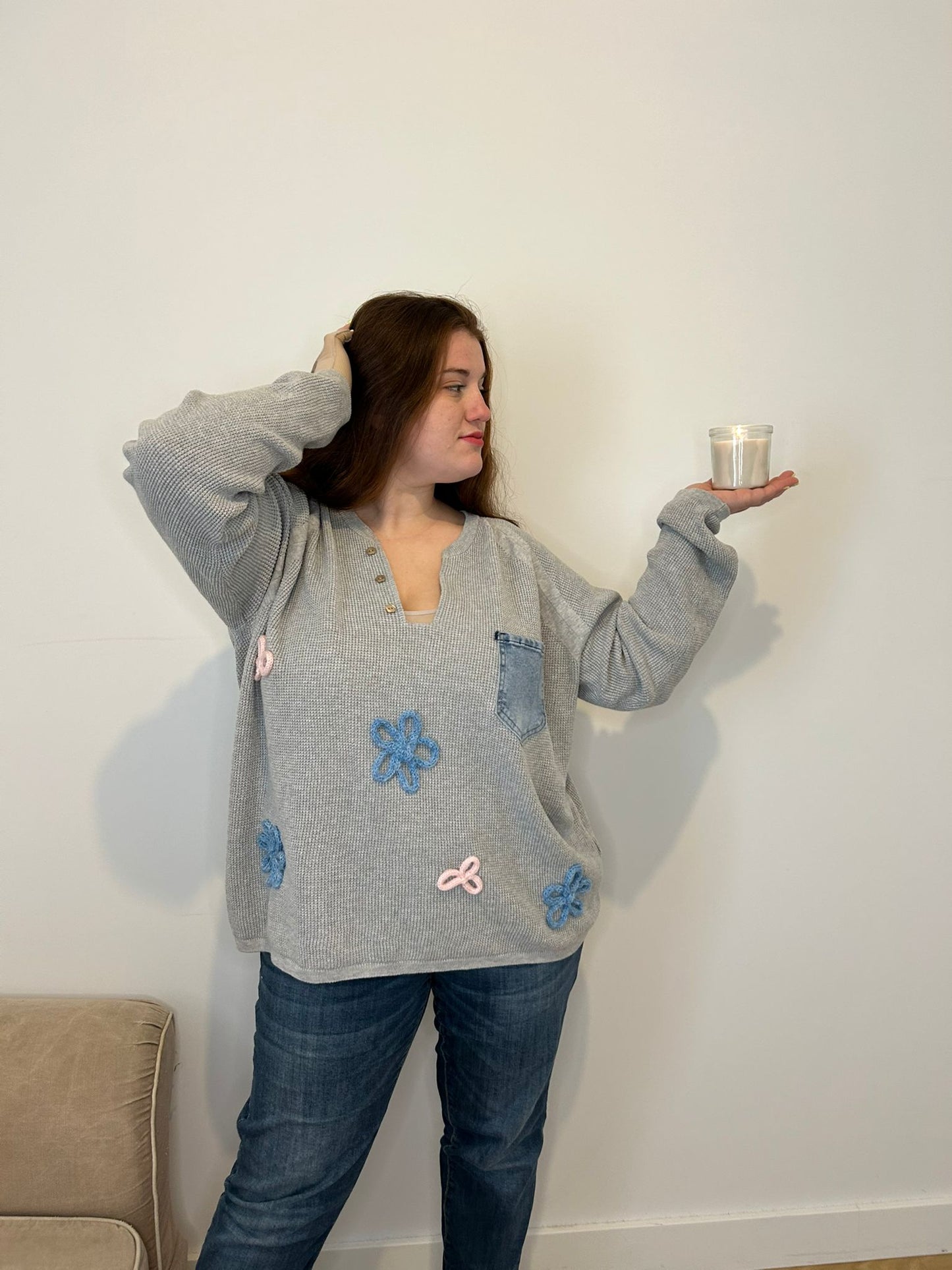pull gris col ouvert fleur et poche en jean, femme grande taille tenant une bougie dans sa main 