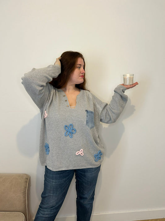 pull gris col ouvert fleur et poche en jean, femme grande taille tenant une bougie dans sa main 