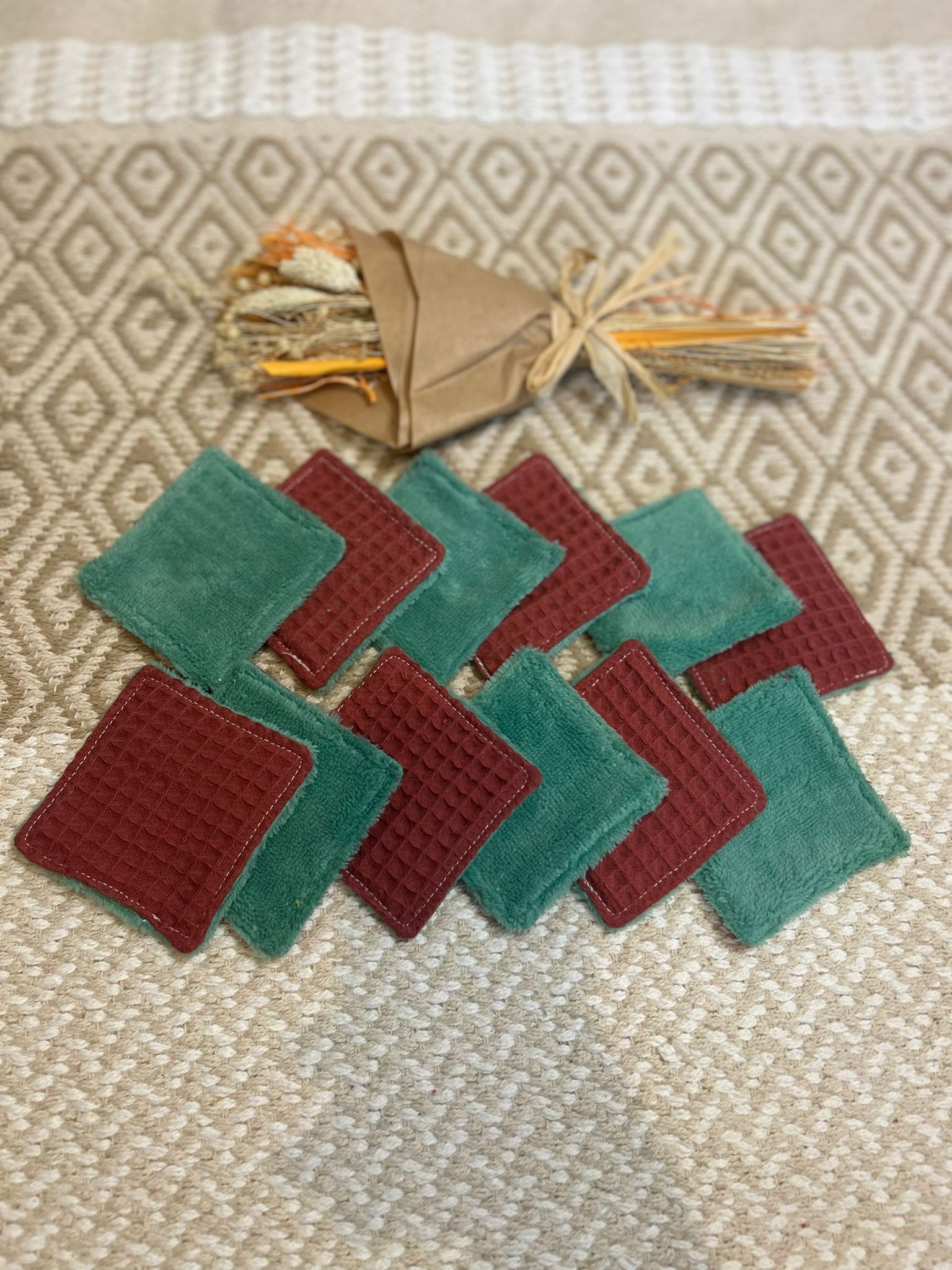 carré de coton démaquillante lavable vert et bordeaux en coton et nid d'abeille, sur une tapis 