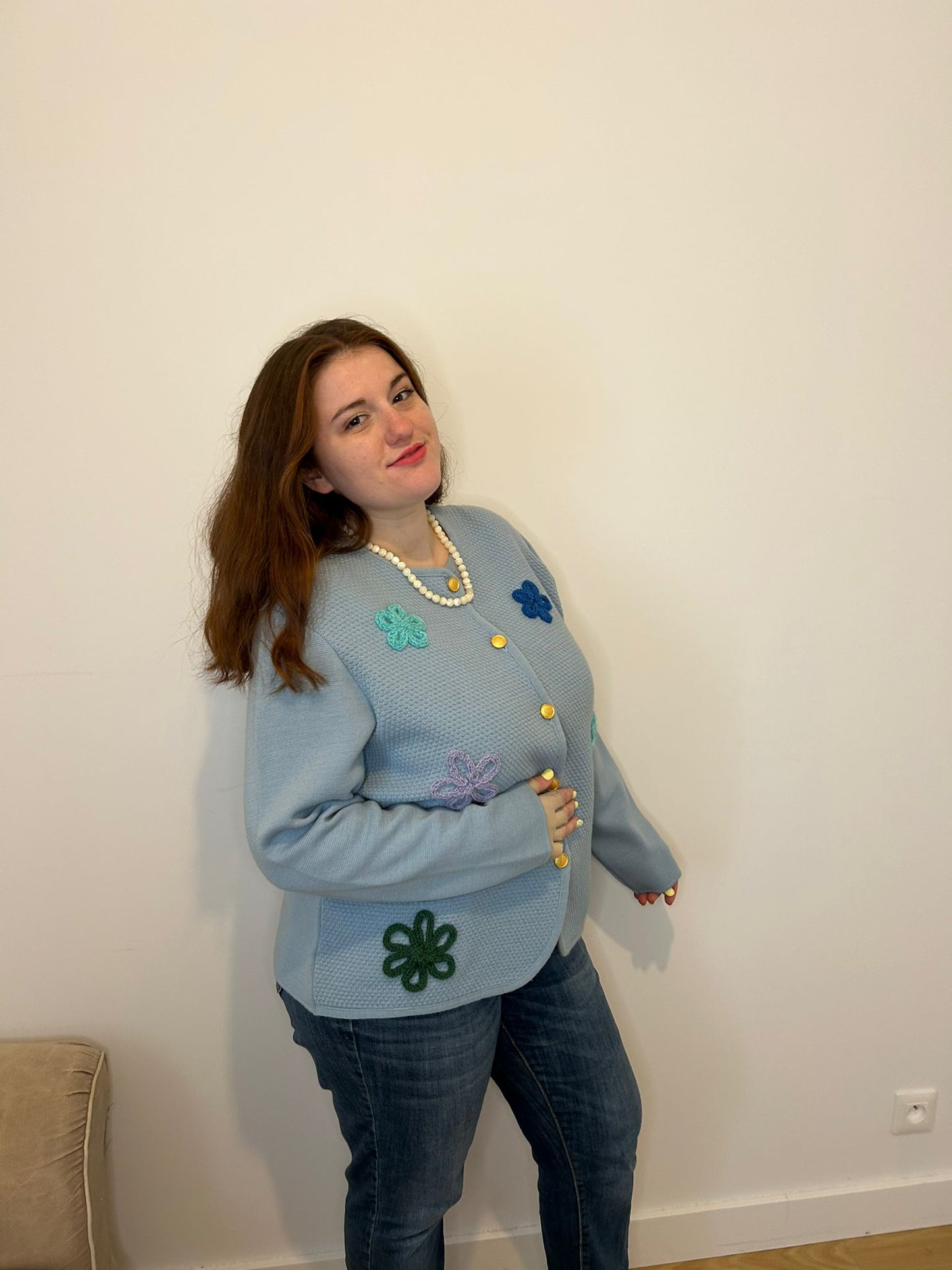 Femme grande taille qui sourit, veste bleu à fleurs elégante et chic, collier de perle blanche 