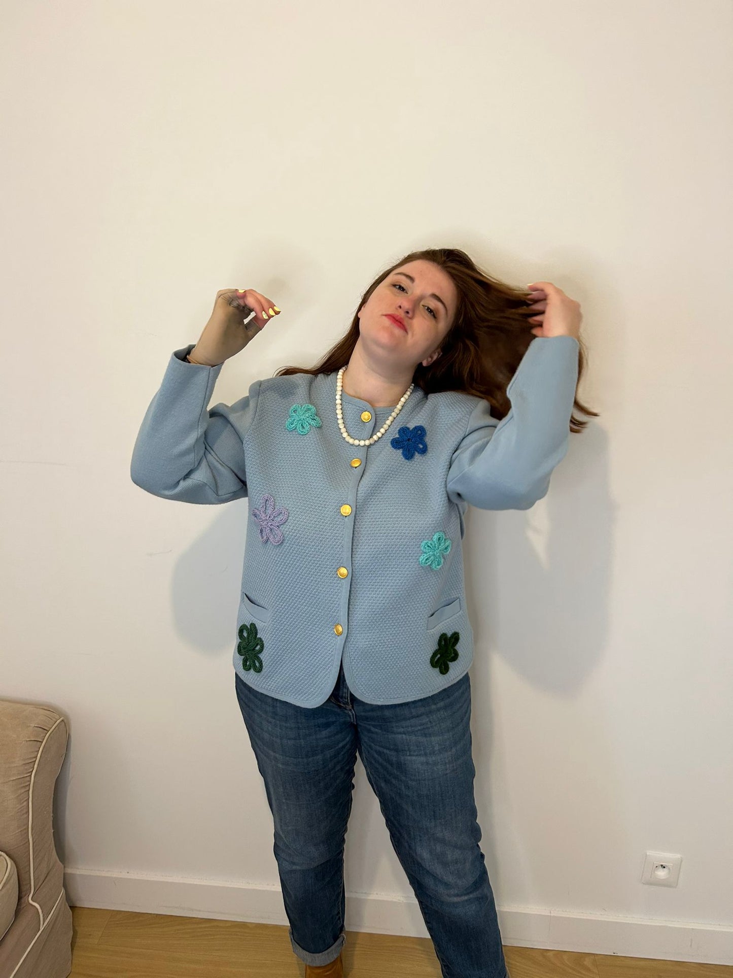 Femme grande taille qui sourit, veste bleu à fleurs elégante et chic, collier de perle blanche 