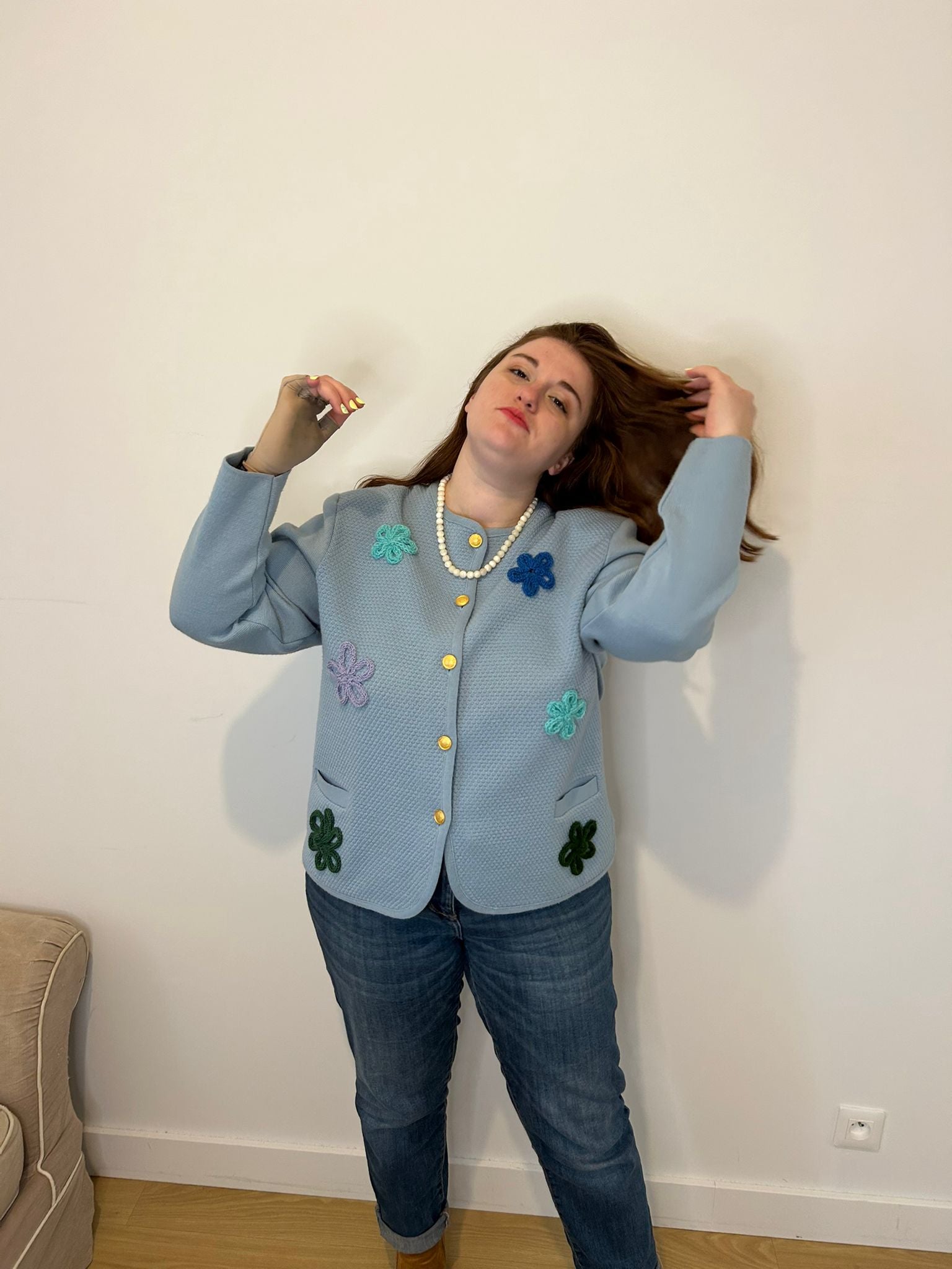 Femme grande taille qui sourit, veste bleu à fleurs elégante et chic, collier de perle blanche 