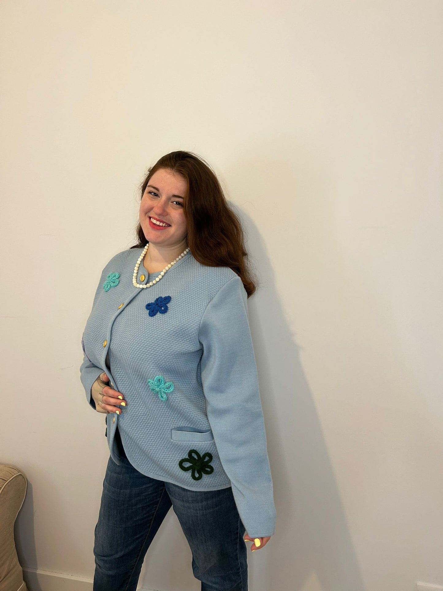 Femme grande taille qui sourit, veste bleu à fleurs elégante et chic, collier de perle blanche 